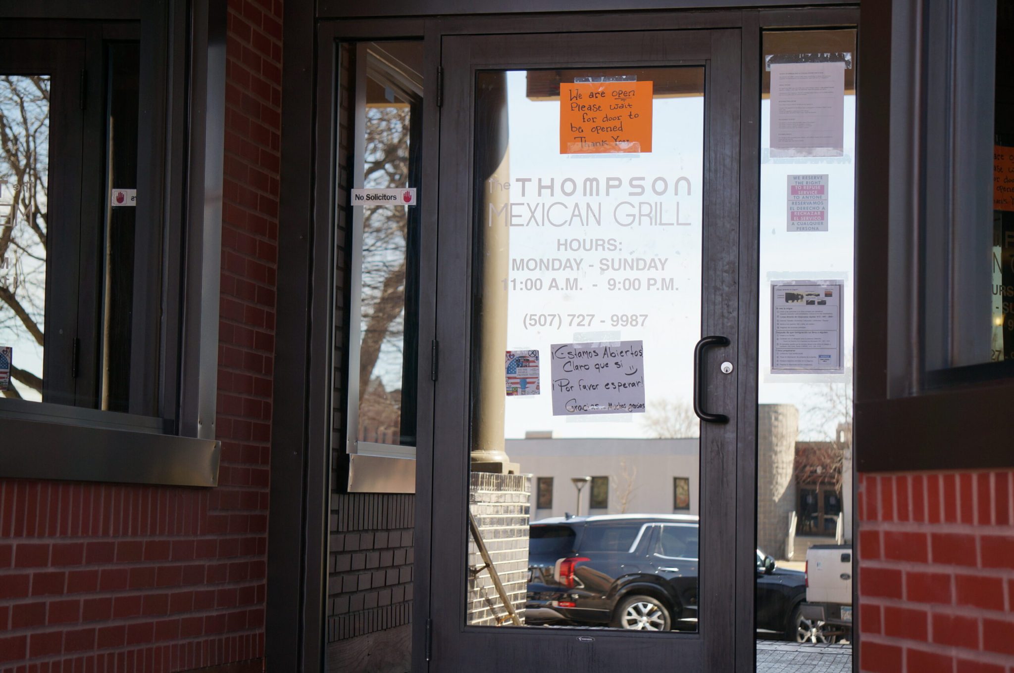 A restaurant with a sign asking customers to wait for staff to open the door