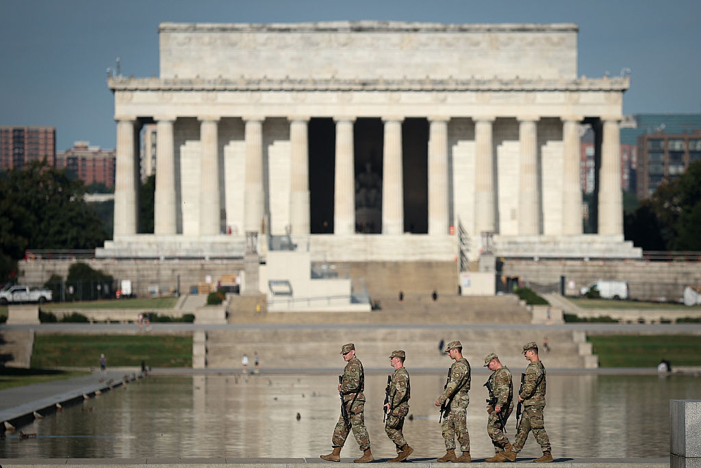 Members of the National Guard carrying rifles patrol near the Lincoln Memorial on the National Mall.