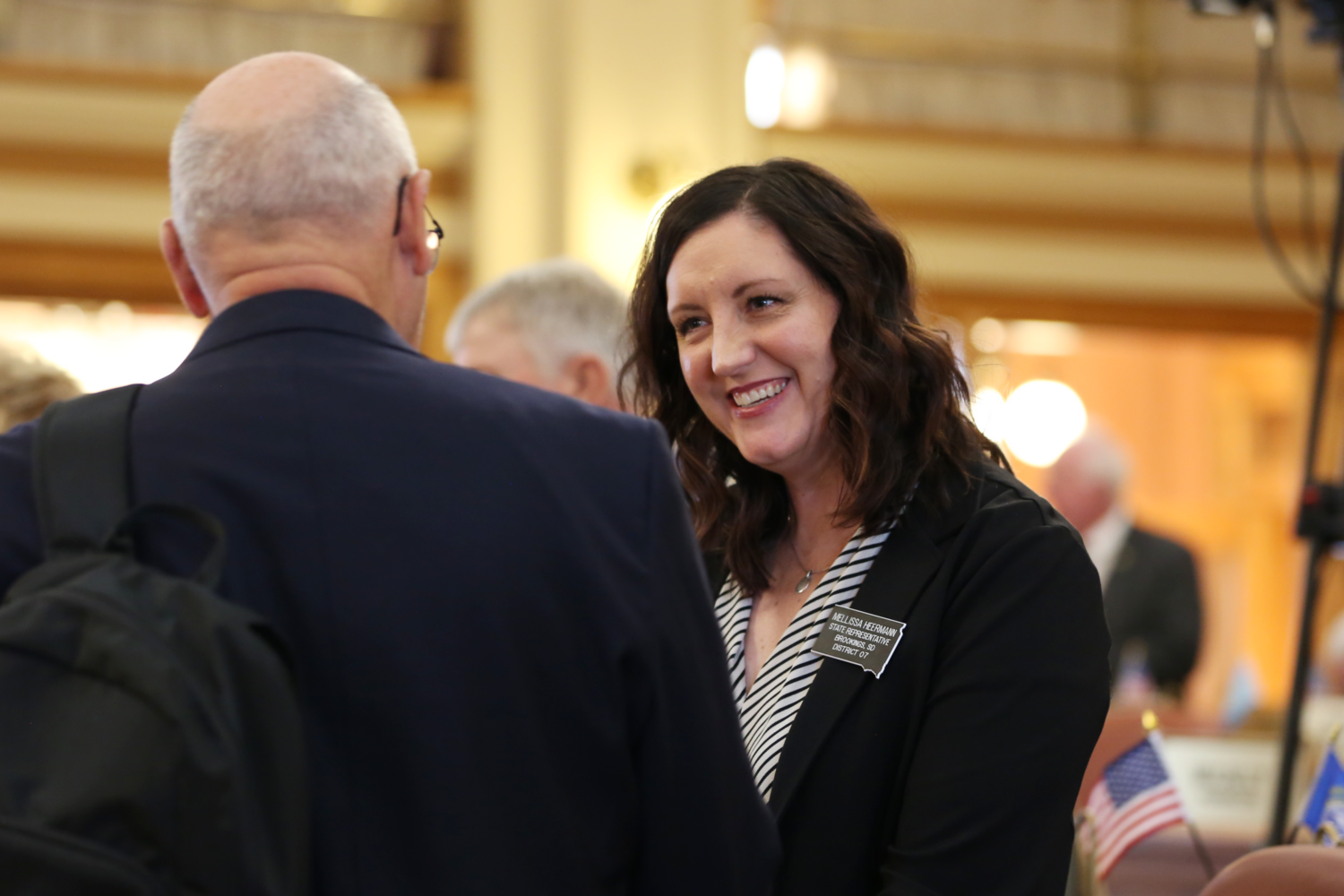 Brookings Republican Rep. Mellissa Heermann greets another lawmaker on the House floor during the governor's budget address on Dec. 3, 2024, at the South Dakota Capitol in Pierre. (Photo by Makenzie Huber/South Dakota Searchlight)