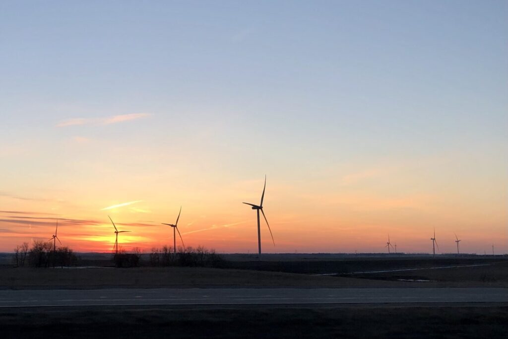 Wind turbines spin against the setting sun just north of Watertown along Interstate 29 in 2023. (Makenzie Huber/South Dakota Searchlight)
