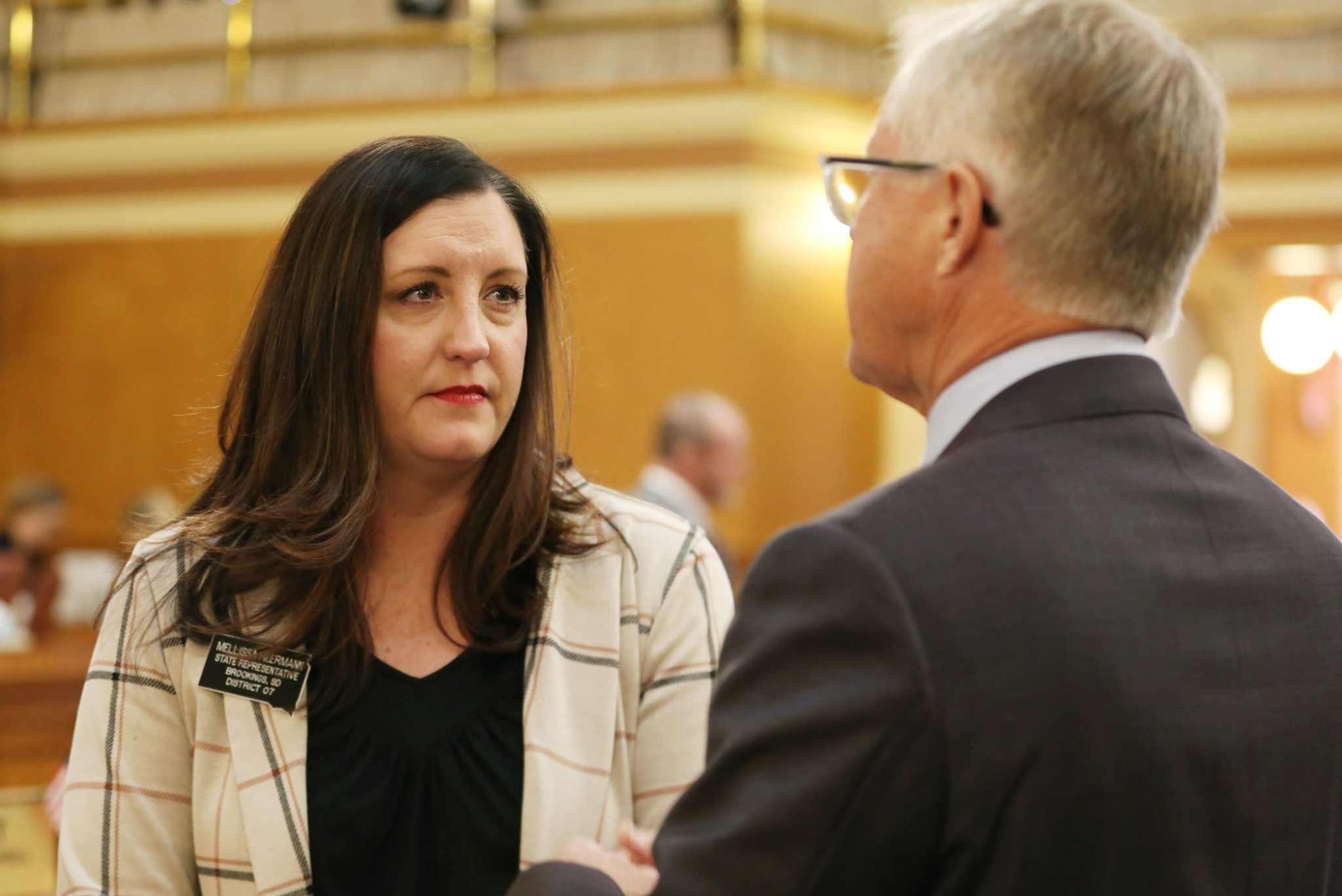 Rep. Mellissa Heermann, R-Brookings, speaks to another lawmaker at the governor's 2025 budget address on Dec. 2, 2025. (Makenzie Huber/South Dakota Searchlight)