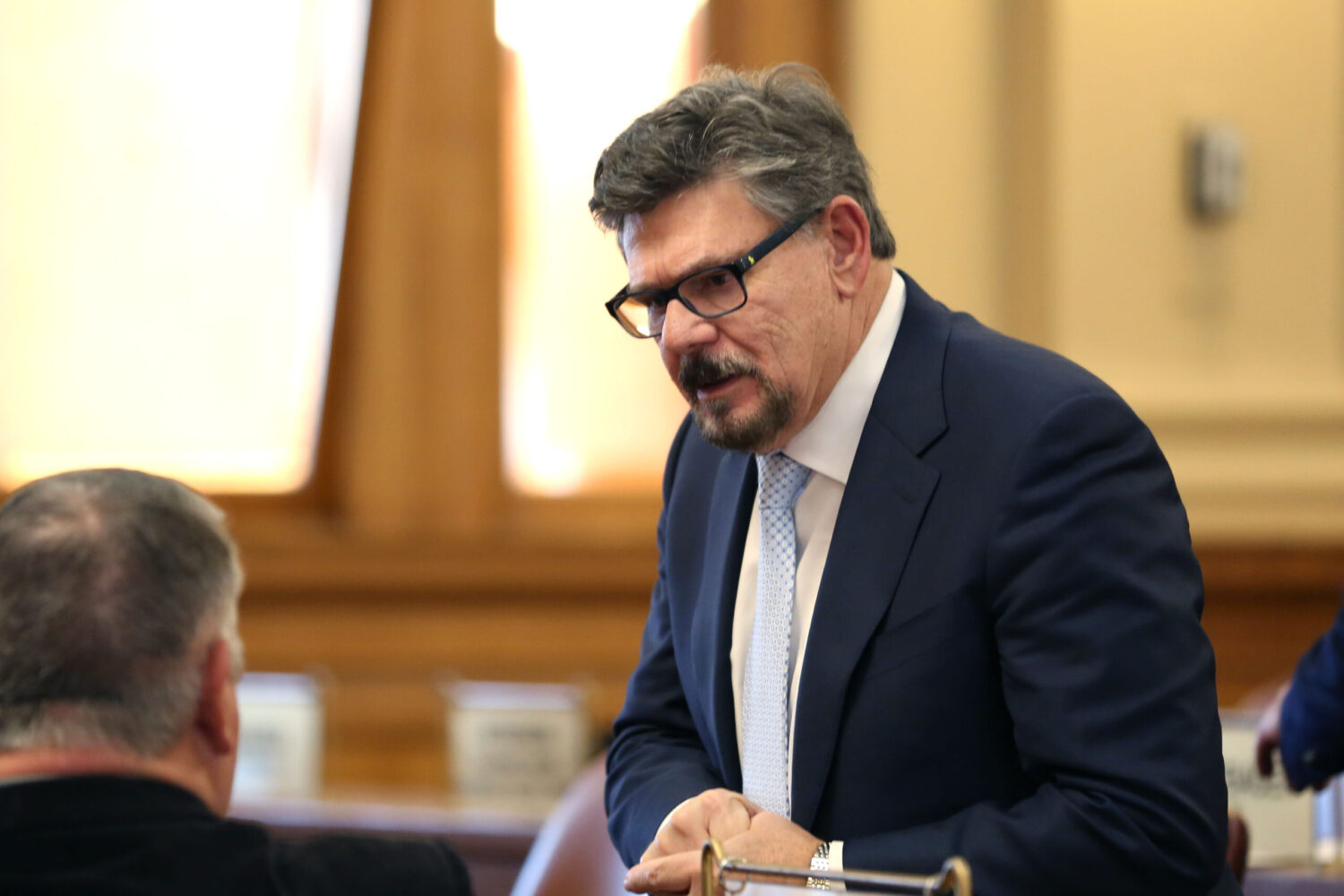Rep. John Hughes, R-Sioux Falls, speaks with another lawmaker on the House floor during the Governor's Budget Address on Dec. 3, 2024. (Makenzie Huber/South Dakota Searchlight)