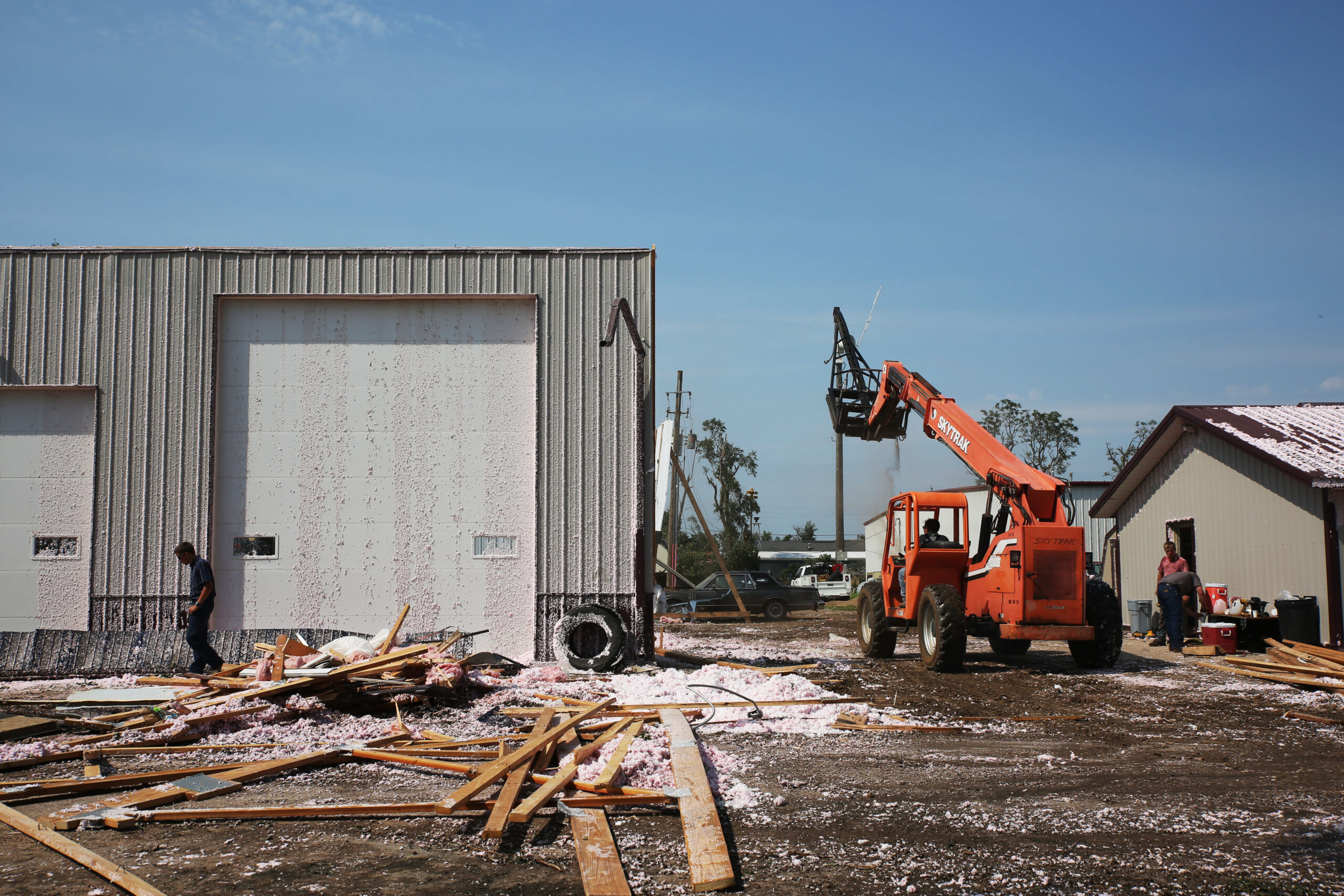 Volunteers help clean up damaged warehouse in Hudson on Tuesday, July 29, 2025 after severe weather blew the roof off of the building Monday evening. The system damaged trees, homes and other structures. (Makenzie Huber/South Dakota Searchlight)