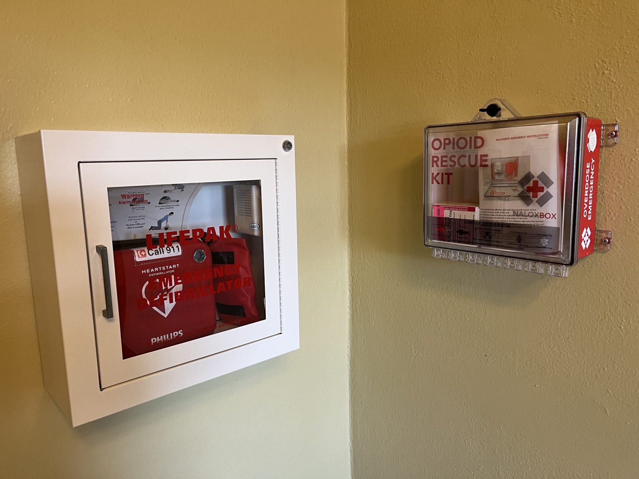 An opioid rescue kit, which includes a naloxone kit inside, is stationed on the third floor of the South Dakota State Capitol, near the Senate chamber, on June 3, 2026. The kit is hung next to an emergency defibrillator, which is used for cardiac arrests. (Photo by Makenzie Huber/South Dakota Searchlight)