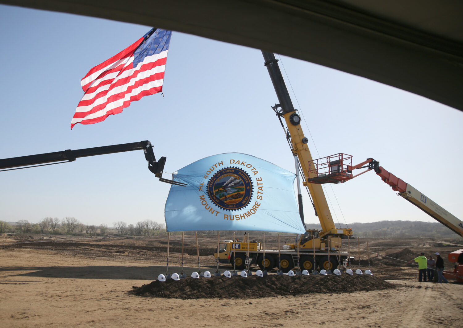 American and South Dakota flags are raised during the groundbreaking for a men's prison in Sioux Falls on April 22, 2026. (Photo by John Hult/South Dakota Searchlight)