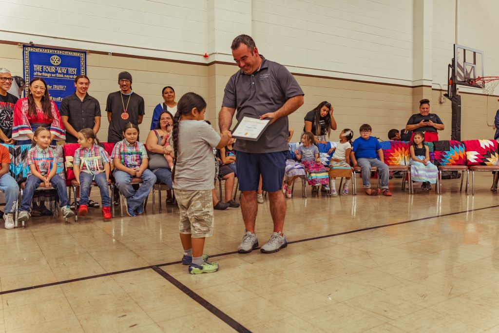 eith Ferguson, Program Manager of Friends of the Children He Sapa congratulate students with a certificate of reading achievement.