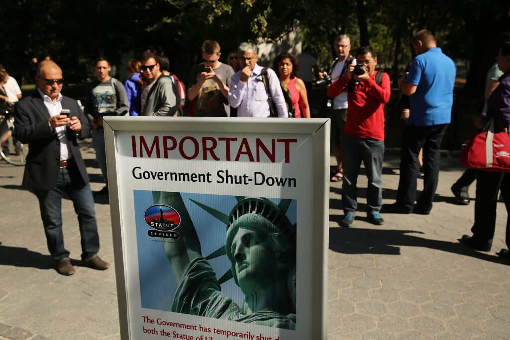 People in New York City look at a sign informing them that the Statue of Liberty is closed on Oct. 1, 2013 due to a government shutdown. Tensions among lawmakers and President Donald Trump, combined with party leaders’ increasing focus on next year’s midterm elections, makes the possibility of a shutdown next month higher than it has been for years. (Photo by Spencer Platt/Getty Images)