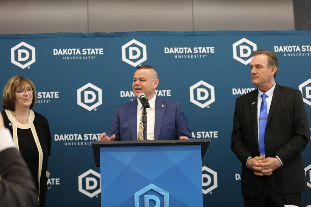 From left, Dakota State University President José-Marie Griffiths, Wyoming financial planner Reid Rasner and South Dakota Gov. Larry Rhoden participate in an event on May 23, 2025, in Madison. (John Hult/South Dakota Searchlight)